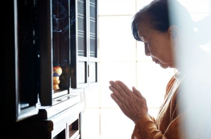 仏壇に手を合わさ慧る女性