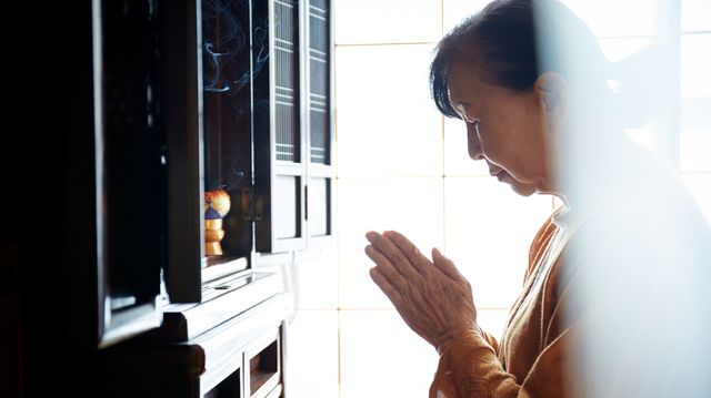 仏壇に手を合わせる女性